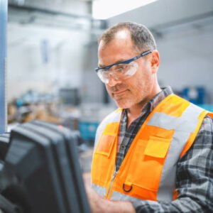 Professional mid-adult industrial factory male employee concentrated, working, putting, checking, and testing with a product line of industrial equipment cables manufacturing plant in a large electronics factory warehouse
